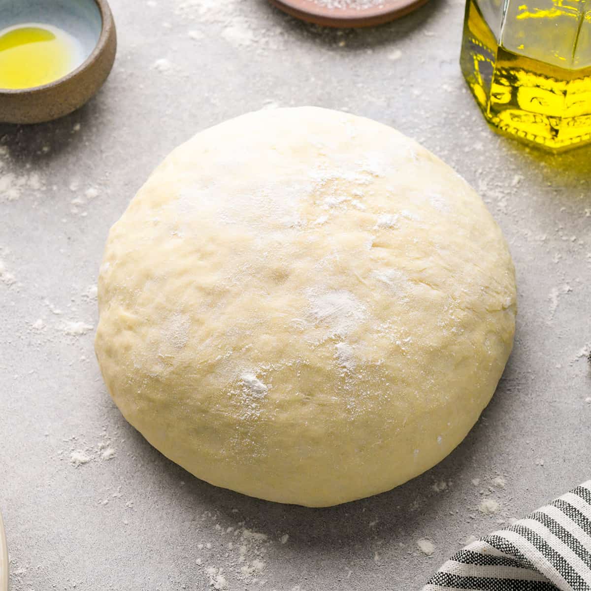 Freshly made pizza dough on a floured surface.